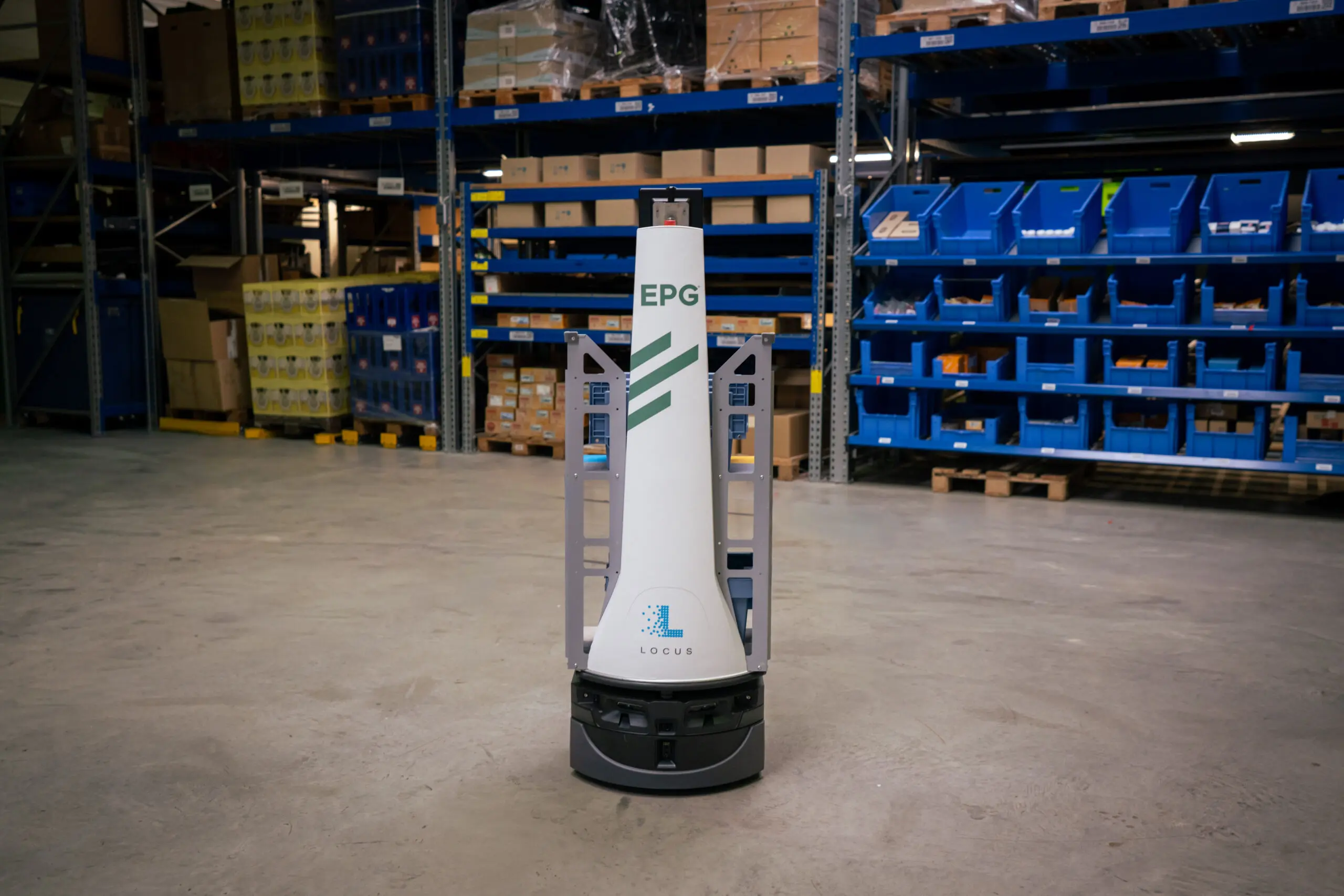 Robotic vehicle in warehouse with shelves of goods.