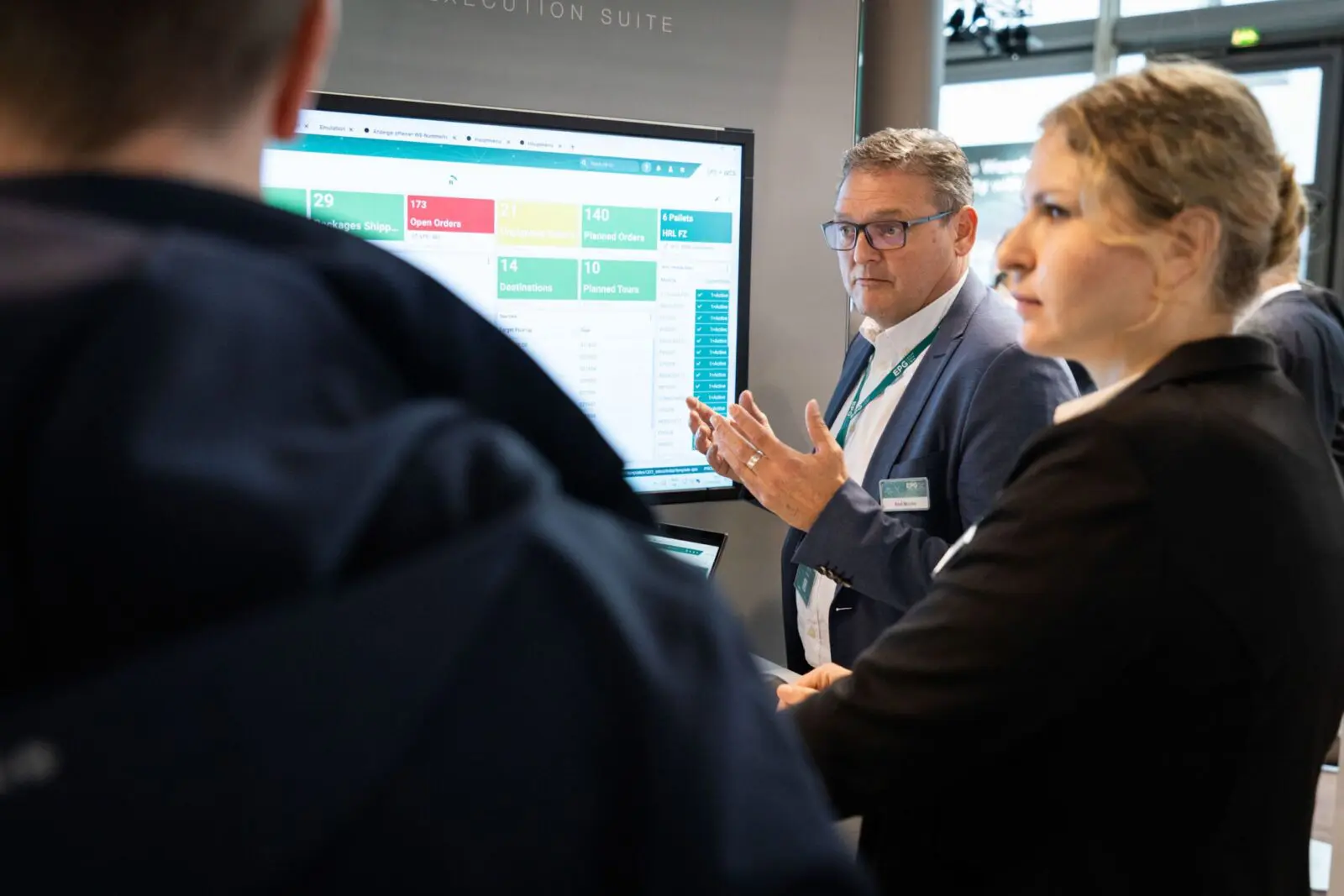 Professionals discuss logistics dashboard at trade show