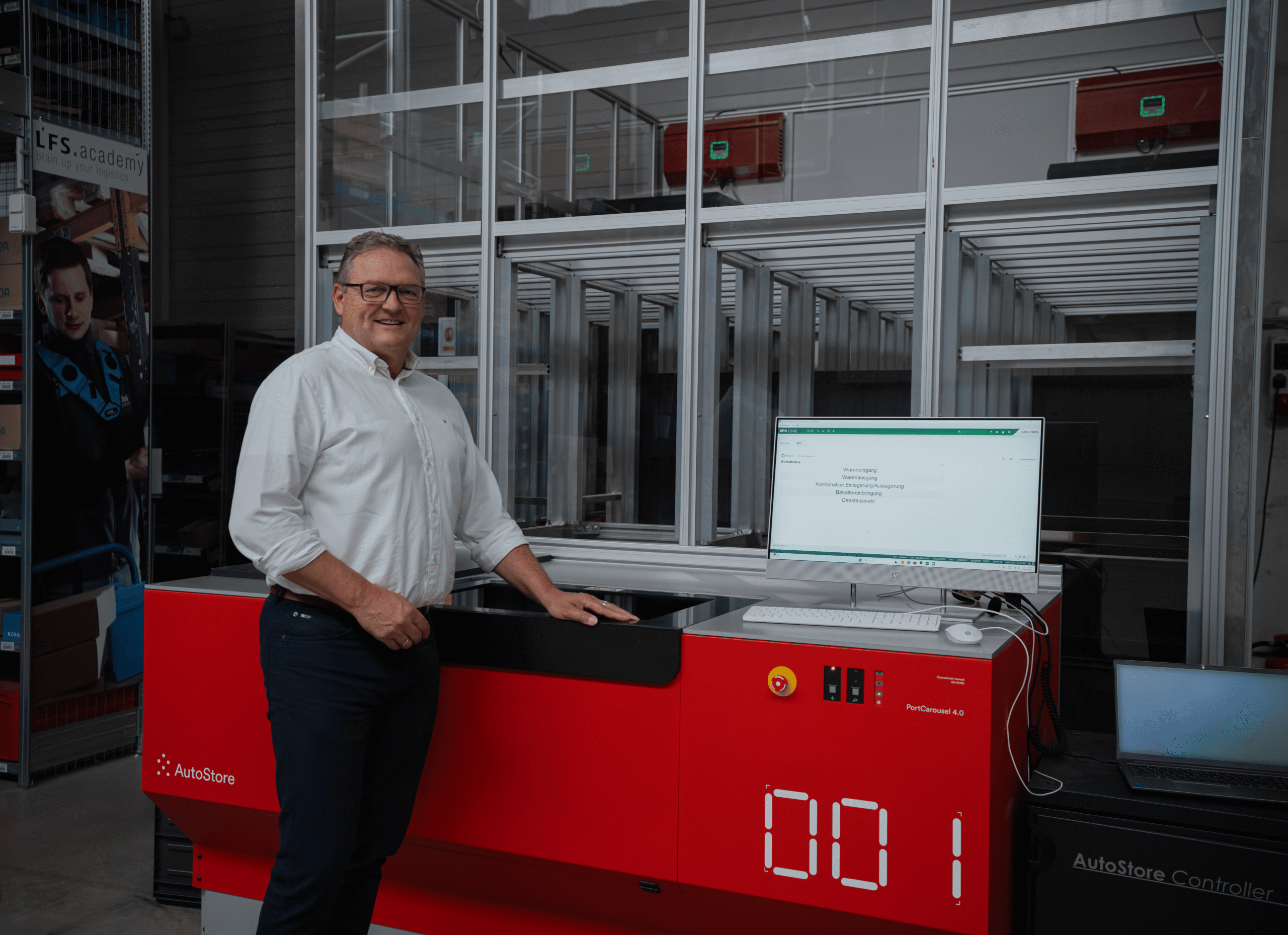 Man standing by AutoStore red robot system in warehouse.