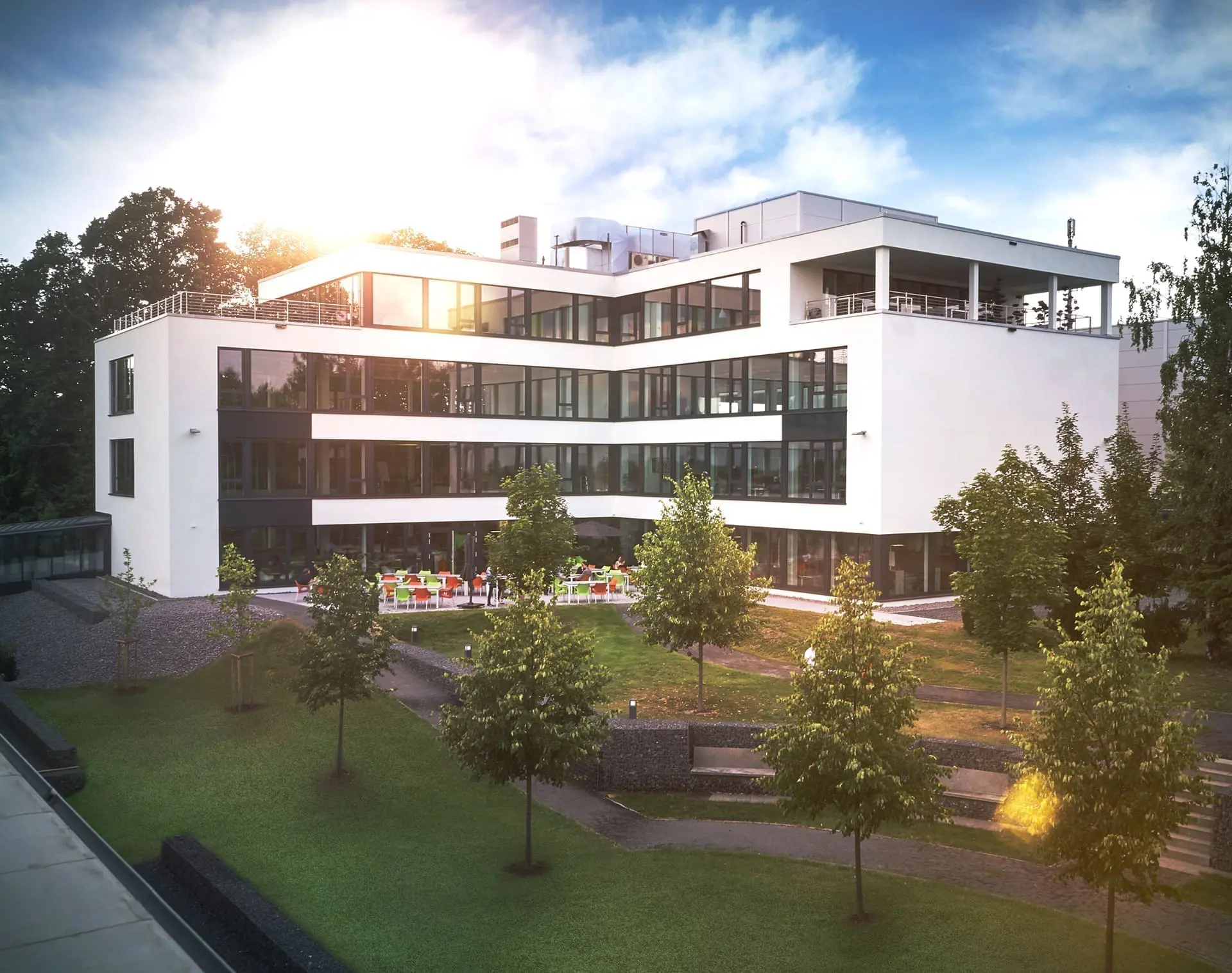 Modern office building with trees and sunlight.