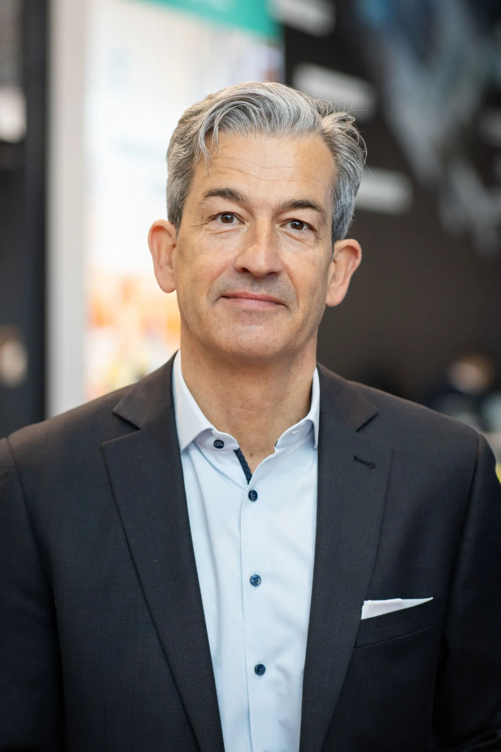 Businessman in suit with neutral expression indoors.