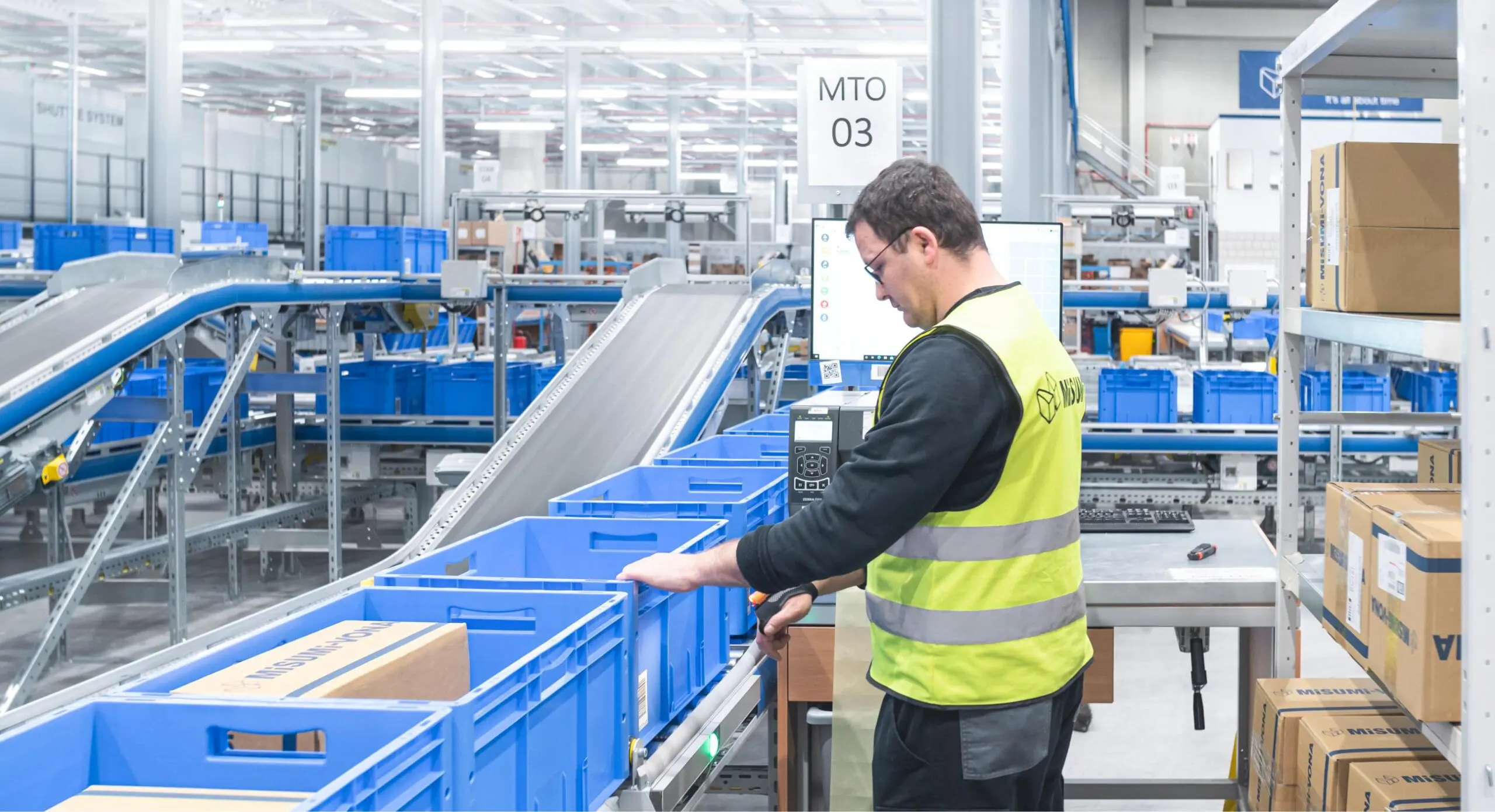 Warehouse worker sorting packages on conveyor belt.
