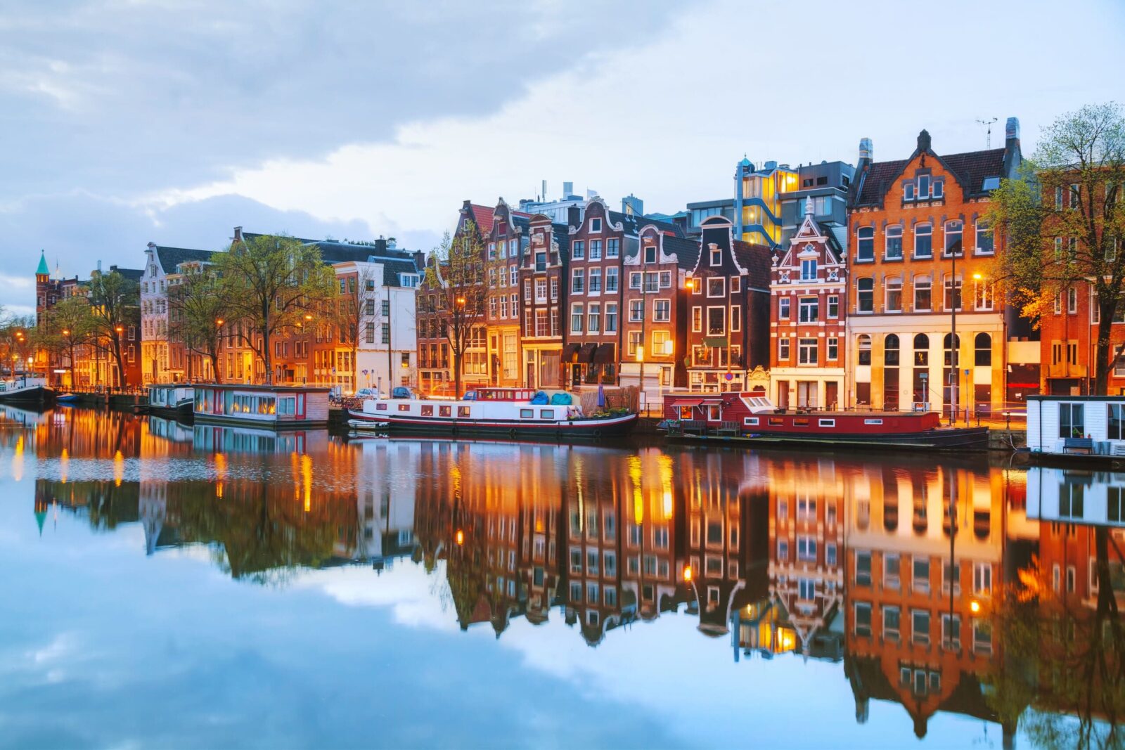 Colorful Amsterdam canal houses and reflections at dusk.