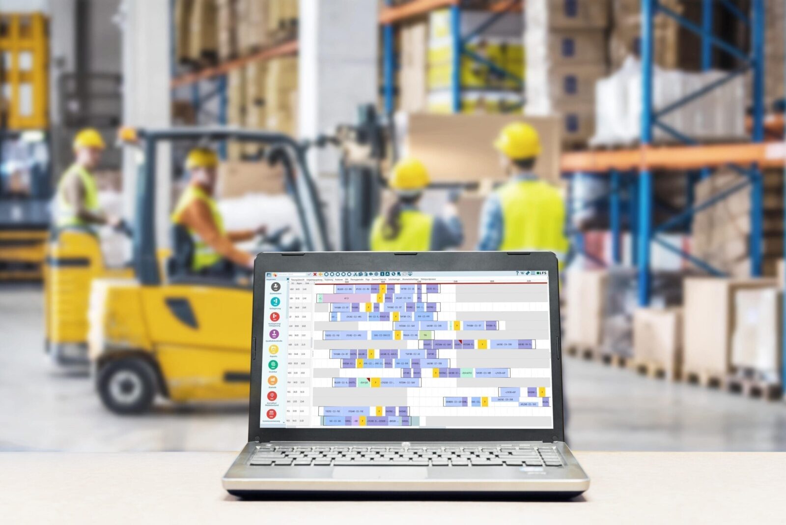 Warehouse management software on laptop in busy warehouse.