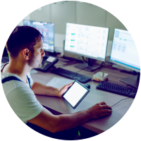 Person monitoring multiple screens in a control room.