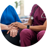 Nurse comforting elderly patient, hands clasped together.