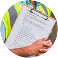 Worker holding clipboard with checklist in safety vest.