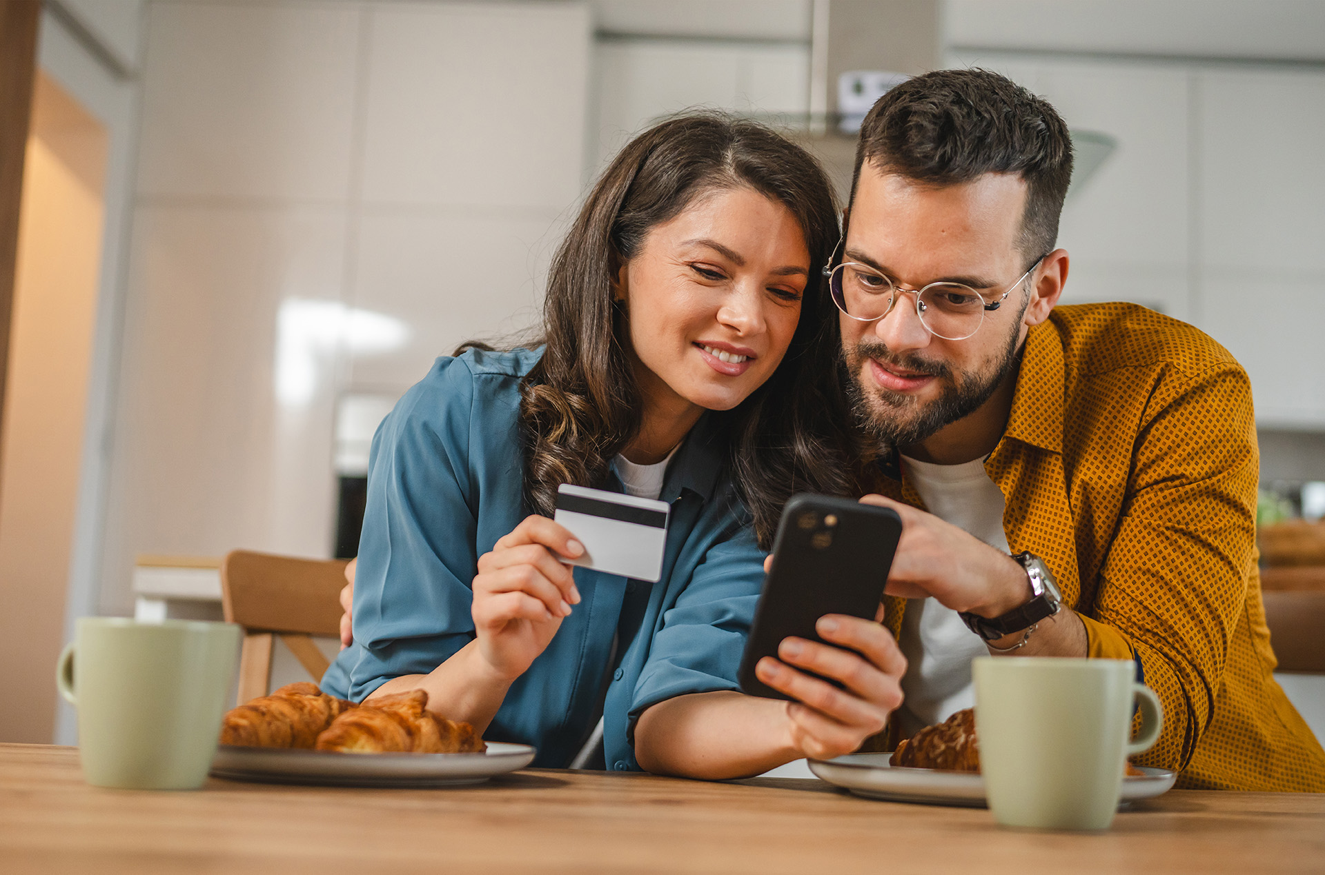 Couple shopping online using phone and credit card.