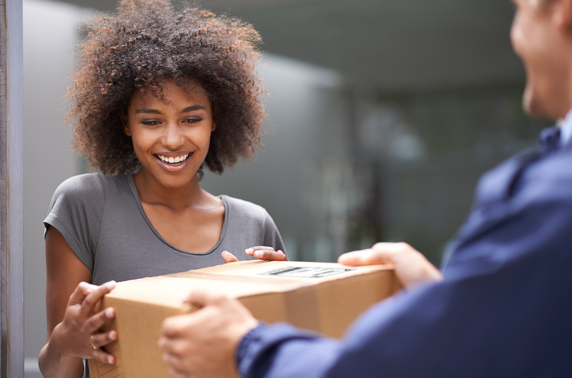 Smiling woman receiving package from delivery person.