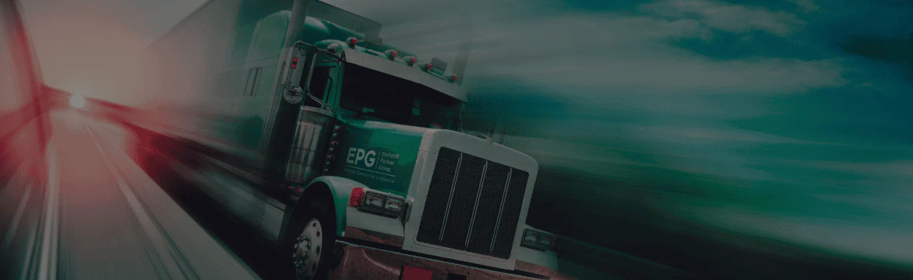 Green semi-truck on highway at sunset