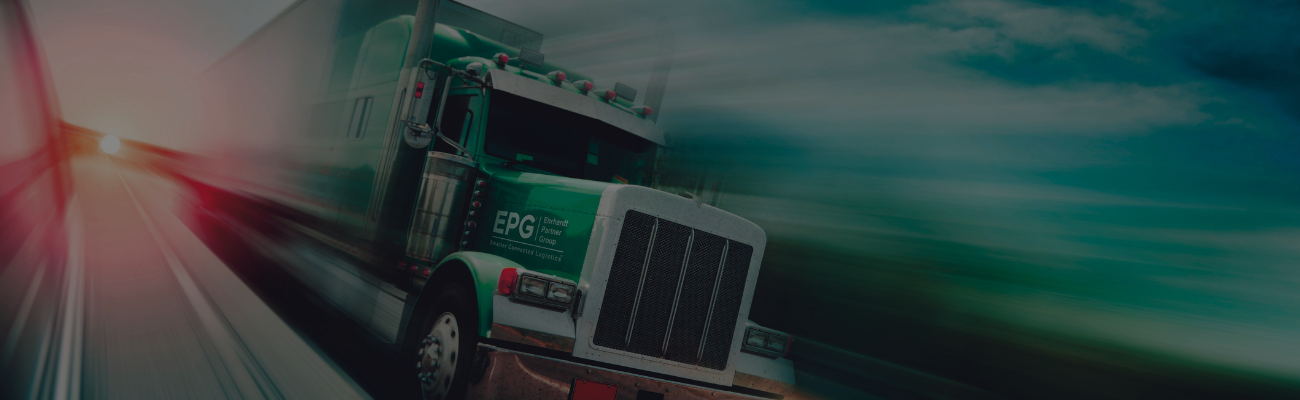 Green semi-truck on highway at sunset