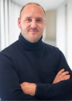 Person in a dark sweater with arms crossed.