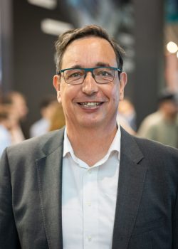 Smiling man wearing glasses and suit at event.