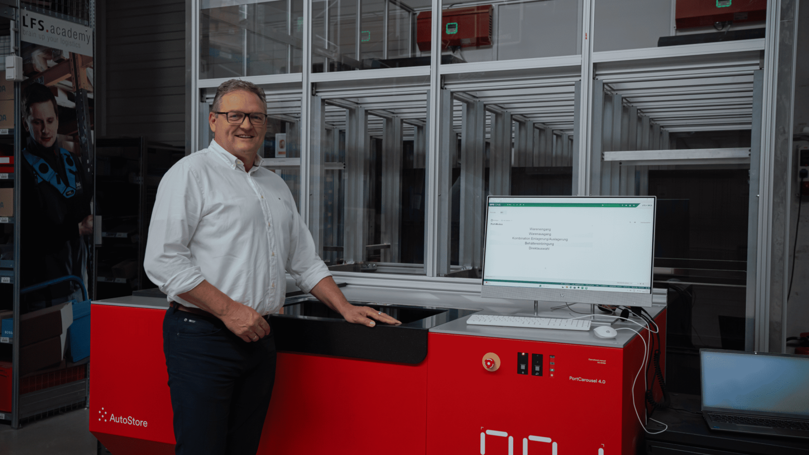 Man standing by AutoStore red robot system in warehouse.