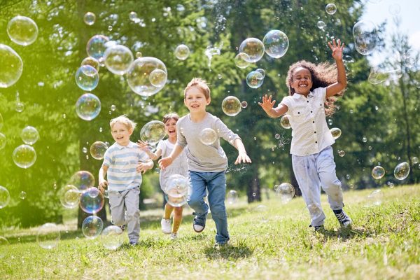 Kinder spielen fröhlich mit Seifenblasen im Park.