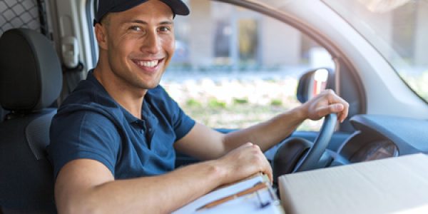 Smiling delivery driver in van with packages