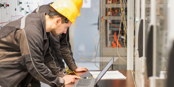 Engineers review electrical systems on laptop.