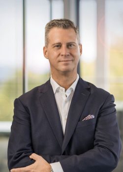 Businessman in suit smiling in office setting.