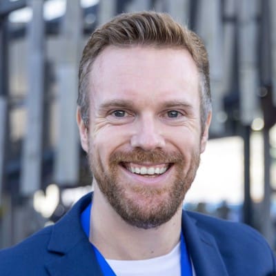 Smiling man wearing blue jacket outdoors.